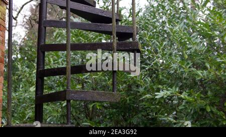 Outdoor black metal fire escape with bushes in the background Stock Photo