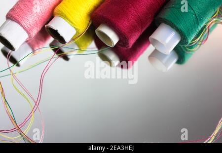 Multicolored threads in the coils are reflected on the surface of the mirror. Sewing and needlework. High quality photo Stock Photo