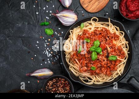 Culinary background with pasta and tomato sauce and fresh herbs on a black concrete background. Stock Photo
