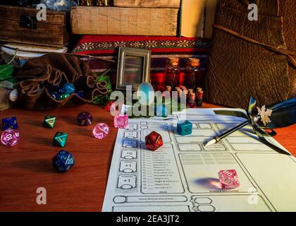 RPG tabletop game attributes, like polyhedral dice, dice bag and potion, on a wooden table in warm light Stock Photo
