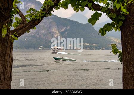 LAKE COMO, ITALY - JUNE 2019: Boats on Lake Como with the view framed by trees Stock Photo