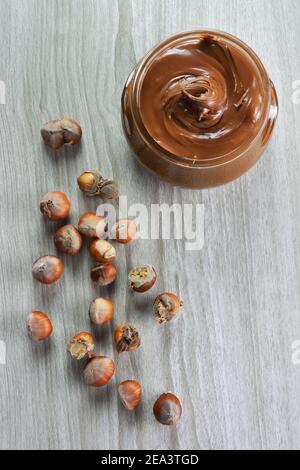 Hazelnuts and vase with hazelnut praline paste on grey table Stock Photo