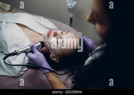 Young woman receiving electric RF lifting facial massage at beauty spa with electroporation equipment Stock Photo