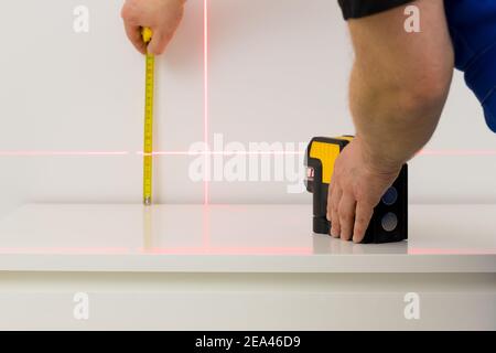 the worker marks right angles and lines during interior measurements Stock Photo