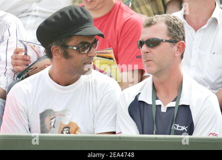 Former French tennis player Yannick Noah, Amelie Mauresmo's coach, and Loic Courteau, attend the match between French players Amelie Mauresmo and Alize Cornet in the second round of the French Open at the Roland Garros stadium in Paris, France, on May 26, 2005. Photo by Gorassini-Zabulon/ABACA. Stock Photo