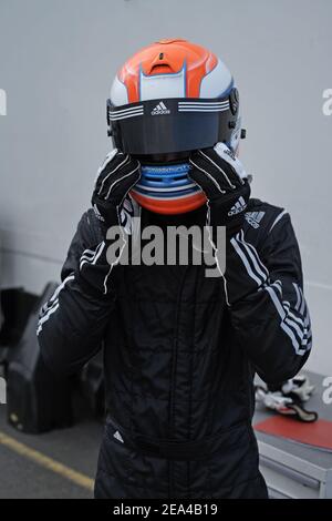 Young racing car driver in racing suiting and helmet. Young man with racing helmet. Racing driver wearing crash helmet standing. Stock Photo