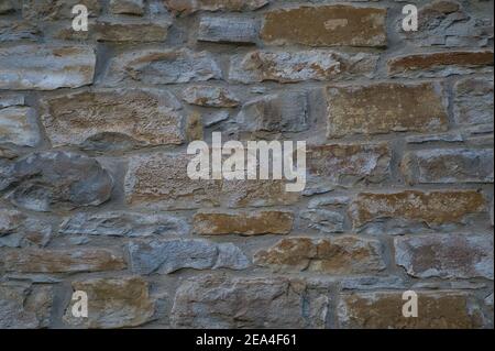 Stone wall of natural stones in different sizes; Rustic stone veneer in shades of brown and beige; Wall covering with natural stones, blue Stock Photo