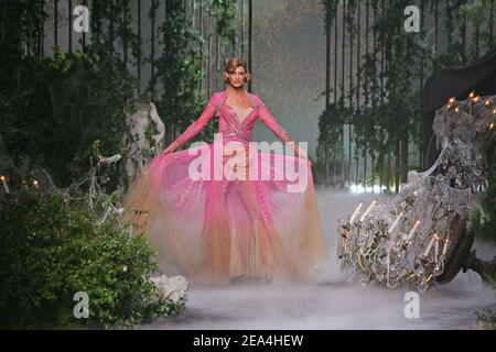 Linda Evangelista presenting a red John Galliano dress in the