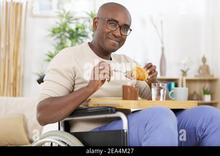 handsome man in wheelchair having breakfast Stock Photo