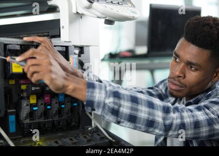 technician using a tablet to fix a printer Stock Photo