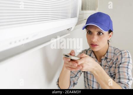 young beautiful woman setting air conditioner at home Stock Photo
