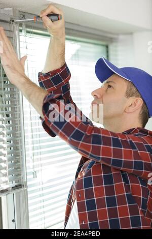 a contractor installing window blinds Stock Photo