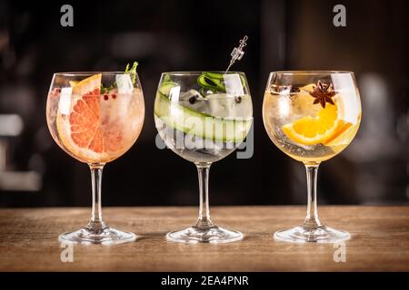Gin tonic long drink as a classic cocktail in various forms with garnish in individual glasses such as orange, grapefruit, or cucumber. Stock Photo