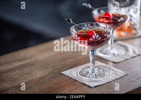 Manhattan classic cocktail as a short drink aperitif with whisky, vermouth, angostura aromatic bitter and cherry garnish. Stock Photo