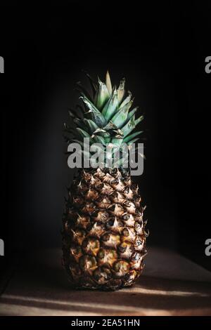 Whole pineapple fruit on the table. Black background Stock Photo