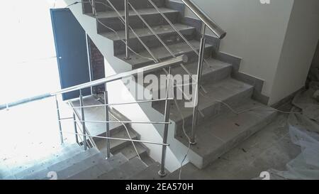 Renovation work in a residential building, handrails are installed on the stairs, chrome-plated handrails in the entrance. Stock Photo