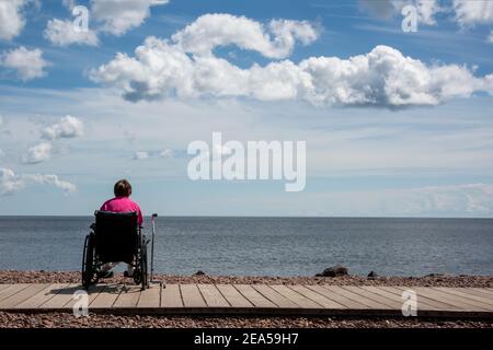 Duluth, Minnesota. A 67 year old woman in a wheelchair sits alone looking out over Lake Superior. Stock Photo