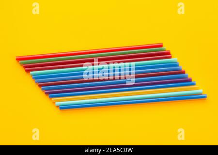 A dozen multi-colored cocktail tubes lie on a yellow background Stock Photo