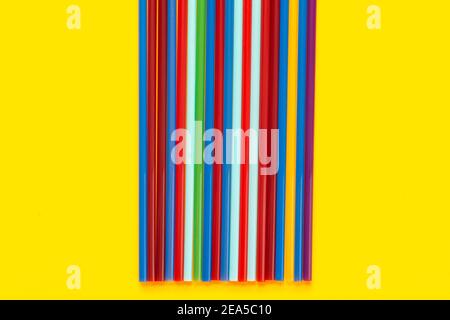 On a yellow background in the middle there are multi-colored cocktail tubes Stock Photo
