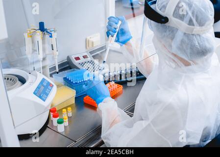 Laboratory assistant in a protective suit and mask in a modern prc laboratory. Stock Photo