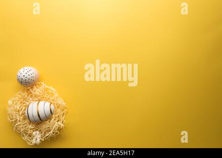 Colored Easter eggs in nest on yellow background Stock Photo