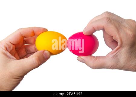 Easter tradition of cracking eggs, two hands hold eggs and try to break each other's egg, close up isolated white background Stock Photo