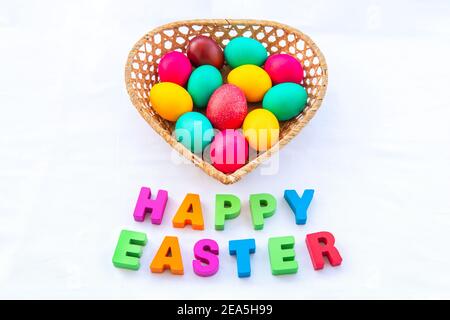 Happy Easter inscription on the table. Easter eggs in the basket on a white background. Stock Photo