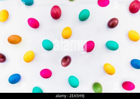 Lots of colorful eggs on a light tablecloth. The concept of the celebration of Easter Sunday in the Christian tradition. Stock Photo