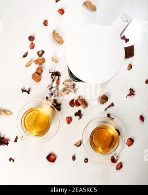 Tea concept, two cups of tea and teapot surrounded with flower petals on white background, view from above Stock Photo
