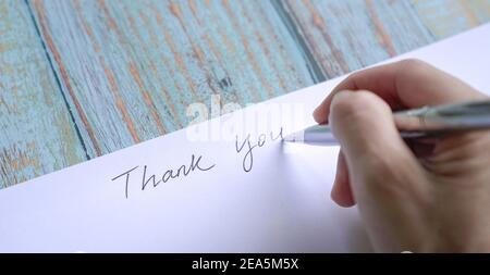 Woman writing thank you on card or paper. Close up view. Stock Photo