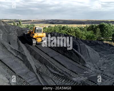 Bulldozer is pushing hard coal. Large coal heap. Stock Photo