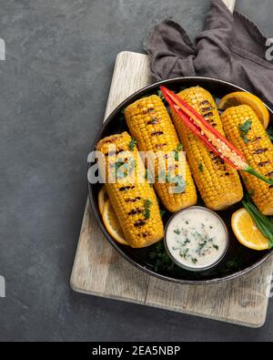 Sweet corn cobs on board grilled with pepper with souce added. Sliced corn in paper bags. Top view with copy space