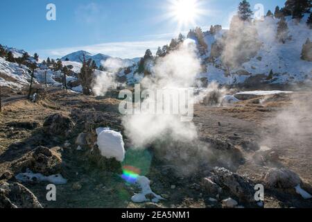 Hot Creek Geological Site is a famous landmark in Mono County. The hot springs, steam vents, curvy stream and mountain peaks create a beautiful scene. Stock Photo