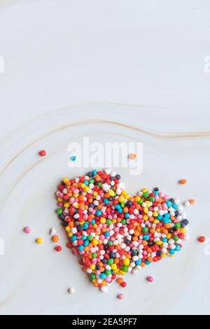 Creative holiday concept of love. Heart shape made from small colorful candies on a white marble background. Valentine's Day concept. Pregnancy Diabetes Concept. Top view, flat lay. High quality photo Stock Photo