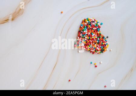 Creative holiday concept of love. Heart shape made from small colorful candies on a white marble background. Valentine's Day concept. Pregnancy Diabetes Concept. Top view, flat lay. High quality photo Stock Photo