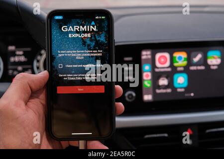 Garmin explore logo on the screen of smart phone in mans hand on the background of car dashboard screen with application of navigation or maps Stock Photo