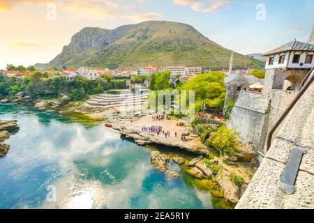 View of the riverbank and Neretva River from the Old arched Mostar Bridge or Stari Most in the medieval village of Mostar, Bosnia and Herzegovina. Stock Photo