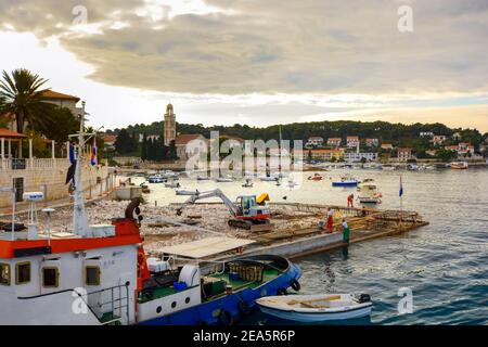 Works and construction crews alongside a small boat as they work on the port of Hvar, Croatia, on of the islands on the Dalmatian Coast of Croatia. Stock Photo