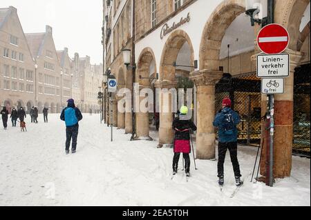 07 February 2021, North Rhine-Westphalia, Münster: A couple is on the move with cross-country skis in the city centre at Prinzipalmarkt. Up to 30 centimetres of snow had fallen in East Westphalia and in Münsterland in the night to Sunday within a few hours. Photo: Ute Friederike Schernau/dpa Stock Photo