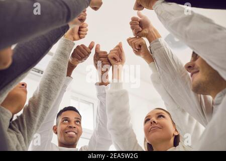 Team of happy young friends or business colleagues giving thumbs-up all together Stock Photo