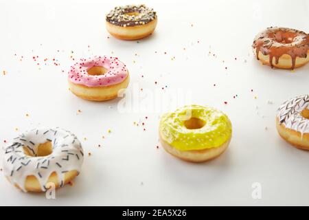 Multicolored donuts with frosting and sprinkles on white background. Stock Photo