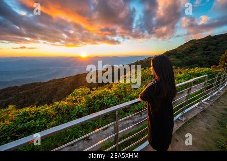 Tropical forest nature landscape view with woman toursit looking sunset mountain range at Doi Inthanon, Chiang Mai Thailand
