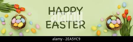 Stylish background with colorful easter eggs pastel colors isolated on green background. Horizontal long banner for web design. Flat lay, top view Stock Photo