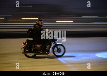 Dresden, Germany. 08th Feb, 2021. A man rides a moped down a snowy downtown street in a snowfall. Credit: Robert Michael/dpa-Zentralbild/dpa/Alamy Live News Stock Photo