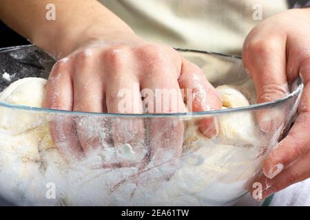 Kneading yeast dough. Woman's hands are holding pastry. Woman kneads dough for bread. Rustic style. Stock Photo