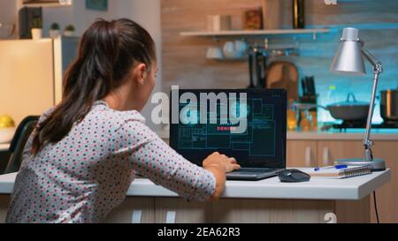 Angry female hacker of failing closing laptop working from home at computer. Programmer writing a dangerous malware for cyber attacks using performance pc during midnight. Stock Photo