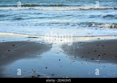 Sea beach with blue waves and shallow water on the wet sand, seascape background for vacation and travel themes, copy space, selected focus, narrow de Stock Photo
