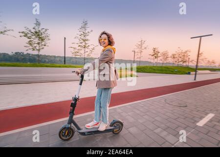 woman riding modern electric sharing scooter. Urban Lifestyle and transport concept. Motion blur Stock Photo