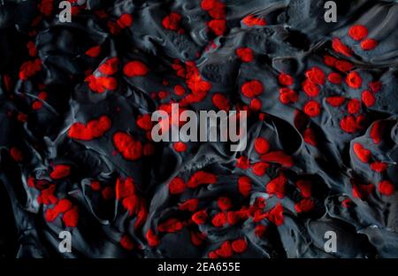 Carbon Black volumetric brutal background with deep red splashes in hard light highlighting the relief. Acrylic liquid foam with ink splashes drops. Stock Photo
