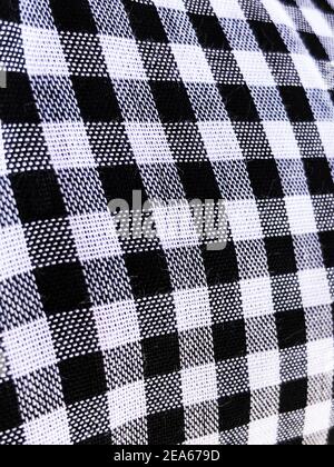Wrinkled material plaid. Black and white checkered shirt fabric background. Button on fabric Stock Photo